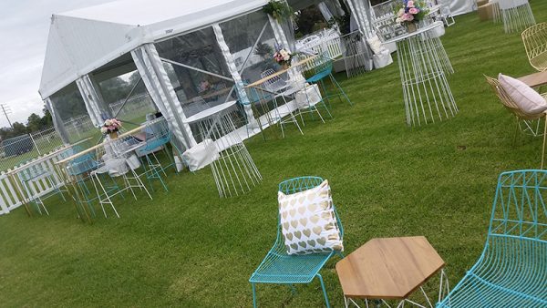 an outdoor event with wired furniture and marquee set up