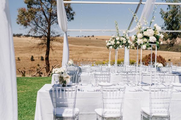 outdoor wedding reception with white tables and clear tiffany chairs 