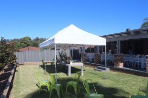 backyard party set up with white pop up marquee and green tolix chairs