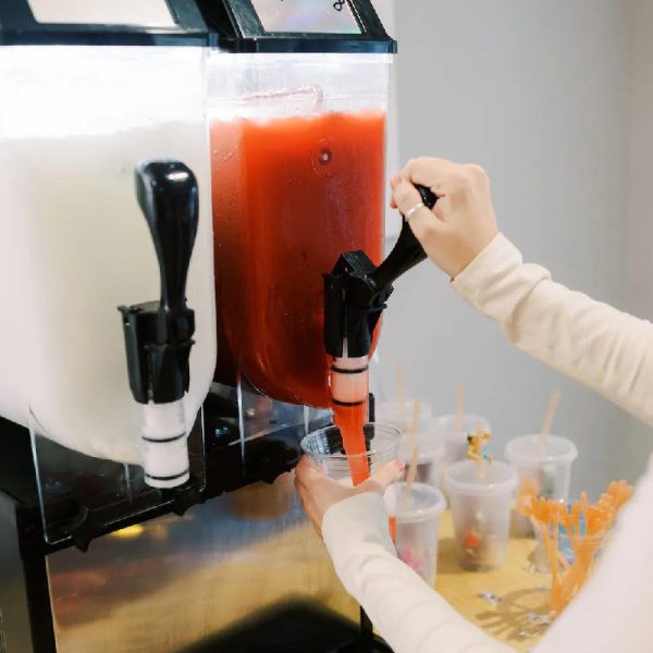 female getting a slushie drink with a twin bowl slushie machine