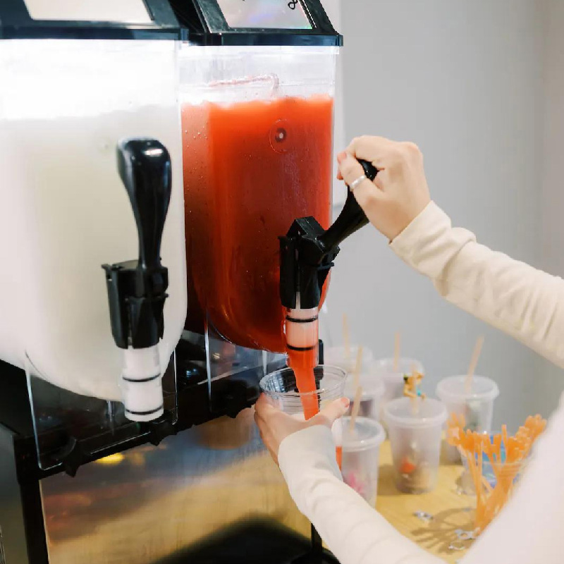female getting a slushie drink with a twin bowl slushie machine