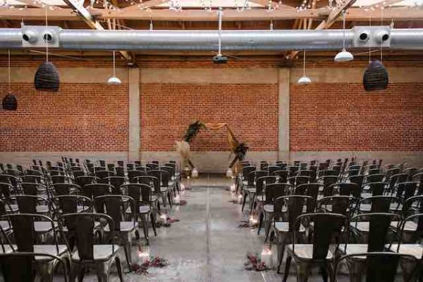 an industrial theme wedding ceremony set up with black tolix chairs 