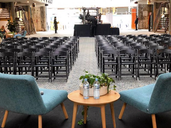 business event with black padded folding chairs and a stage set up with coffee table and lounges
