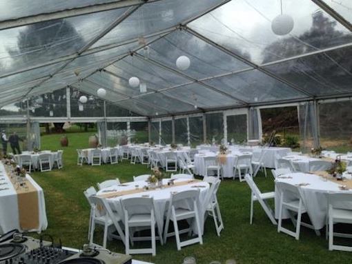 white rice lantern hanging from marquee with white round tables and white padded folding chairs